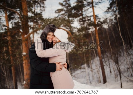 Happy couple having fun, smiling, kissing outdoors in winter against a forest background. Concept people, love, leisure