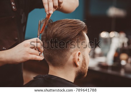 Close-up, master hairdresser does hairstyle and style with scissors and comb. Concept Barbershop. Royalty-Free Stock Photo #789641788