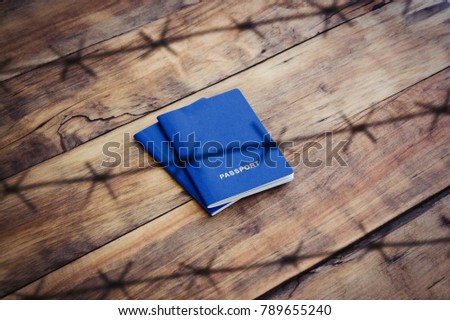 Blue Passport behind barbed wire on a wooden background, close-up, top view.