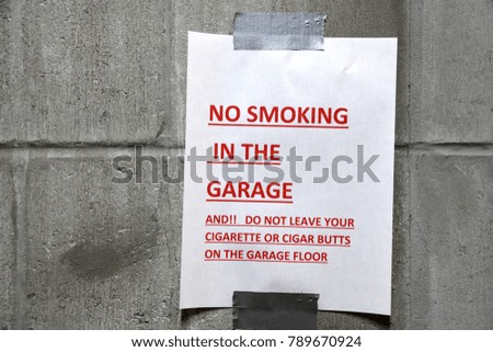 No smoking in garage paper message sign taped on wall