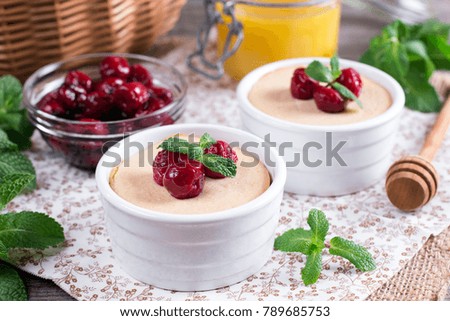 Yoghurt with fresh juicy cherries in white ceramic form on a wooden table