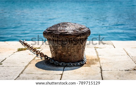 Old rusty steel mooring bollard pole on a pier. The best way for boat or ship mooring in harbor. Croatia, Silba.