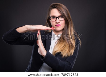 Businesswoman showing time out sign with hands as deadline or pause concept isolated on dark background