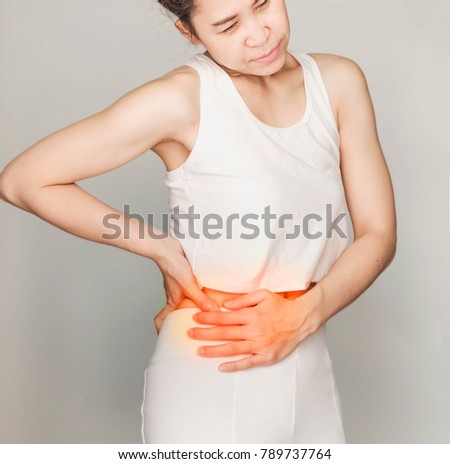 young woman in white clothes , grabbing an right belly, She has stomachache. Health Care Concept.