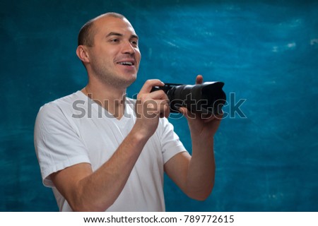Young man wearing casual clothes using professional camera posing on blue vintage background