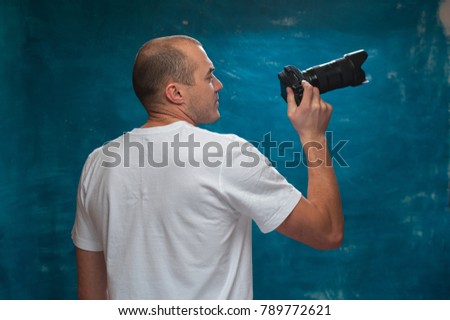 Cute man photographer posing with camera against blue vintage background