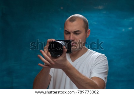 Young man wearing casual clothes using professional camera posing on blue vintage background