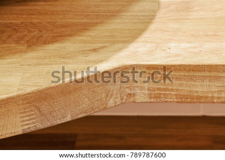 Front view down on flat wooden board with wood texture and complex shape board's edge lit with artificial light, FOCUS ON BOARD'S EDGE