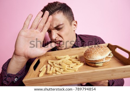 fast food, man with a tray on a pink background, hamburger, potato                               