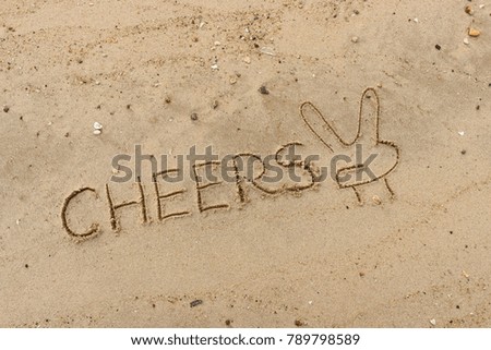 Handwriting  words "CHEERS" on sand of beach.