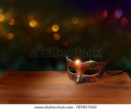 Traditional female carnival venetian mask on table .Masquerade mask on  glitter background.Mardi Gras.
