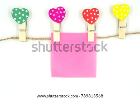 colorful clothespin with heart shape design and pink  paper sheet and rope for valentine concept isolated on white background . Space for text and images .