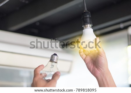 Power saving concept. Asia man changing compact-fluorescent (CFL) bulbs with new LED light bulb.
 Royalty-Free Stock Photo #789818095