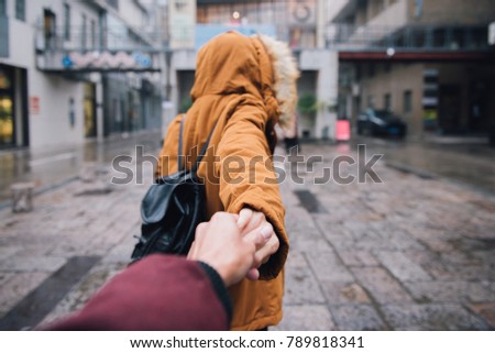Couple woman and man follow holding hands in urban street on background. Love and travel lifestyle concept.