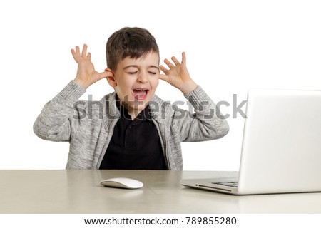 Studio portrait of playful schoolboy in front of laptop