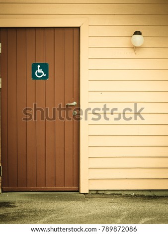 Blue handicapped wheelchair sign on door of public toilet outdoor, WC restroom