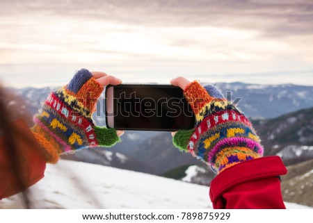 Girl taking picture of beautiful winter scenery with a smart phone
