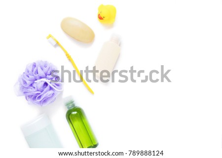 Green shampoo bottle, purple sponge puff, yellow toothbrush, baby soap, rubber duck. Bathroom stuff on a white background. Free space for text. Flat lay bath products, organic cosmetics