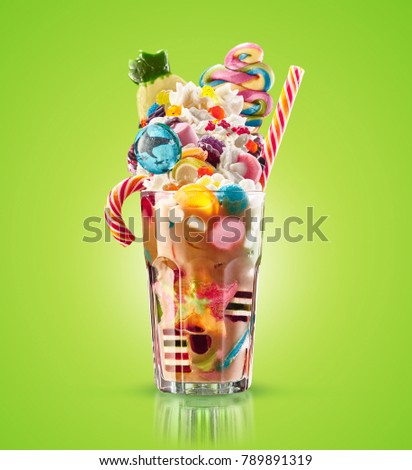 Monster shake, freak caramel shake isolated. Colourful, festive milk shake cocktail with sweets, jelly. Colored caramel milkshake array of different childs sweets and treats in glass on green