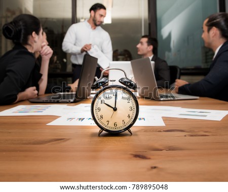 Alarm clock on wooden table with business discussion people group or meeting team background,Retro alarm clock in 10 o'clock ,Time concept at early morning or overtime in evening, Royalty-Free Stock Photo #789895048