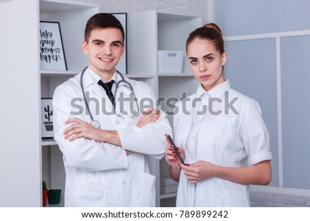 Two young doctors in a white medical robe posing standing. The concept of medicine.