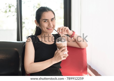 Asian woman relaxing in cafe.
Beautiful young woman drinking coffee with shallow focus.