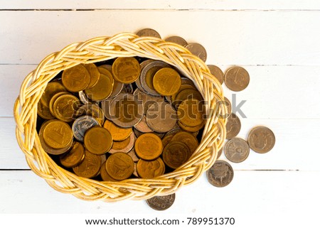 Piles of coins in wood basket on white wooden background.For investment concepts in the business and savings