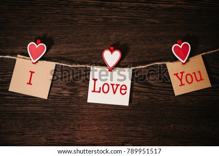 Text I love you. Craft paper, three blank, with red heart hanging on rope on brown wooden background with space. Place for text. concept of St. Valentine's Day. Women's Day, eighth of March.