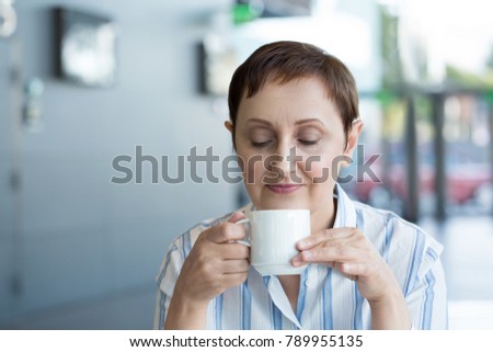 Woman drinking coffee. Older woman holding a coffee or tea cup in a cafe or in the office during coffee break or lunchtime.
