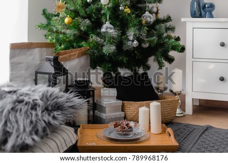 
a cozy interior with pillows, plaid, candles, pine cones, a Christmas tree, gifts,