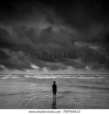 lonely boy  alone looking at the horizon near the beach during storm, black and white photography.
