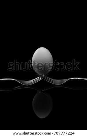 Happy Easter,white egg two forks ancient silver on a black background.