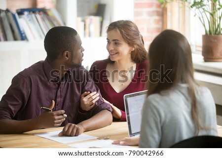 Young diverse couple customers consulting before signing mortgage bank loan investment contract, african husband and caucasian wife make decision about real estate purchase at meeting with realtor