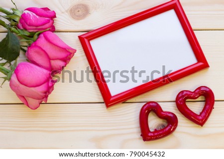 Concept of valentine's day with a bouquet of pink roses and photo frame on wooden background top view
