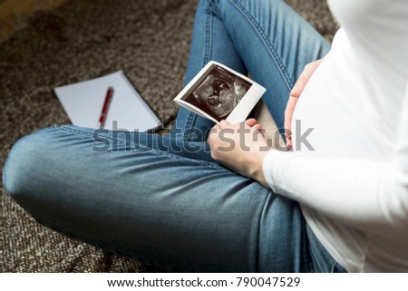 Pregnant woman expecting newborn and holding ultrasound