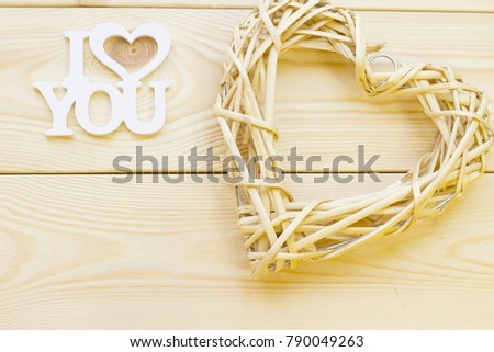 I love you inscription and woven heart wreath on wooden background, close up, top view. Concept of St.Valentine's Day, anniversary, wedding