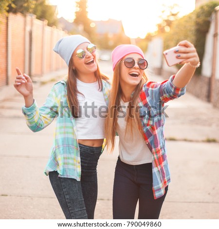 Two cheerful girls takes pictures of themselves on the mobile phone.