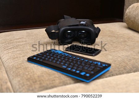 virtual reality glasses with smartphone, keyboard on wooden background