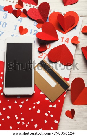 Valentine day internet sales concept, online shopping holiday background, copy space. Smartphone and credit card on white rustic table with marked date on calendar. Card and advertising mockup