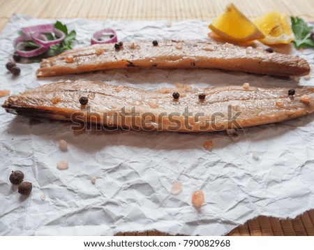 Appetizing salted herring fillet with onion, lemon and spices on a bamboo napkin.