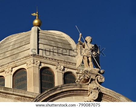 Dome of the basilica with a figure of an angel and blue sky in the background
