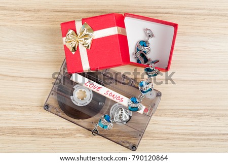 Audio cassette tape with label love songs on wooden background. Valentine postcard, retro color tone
