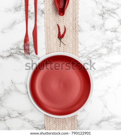 Red dishes and cutlery on the marble table.
