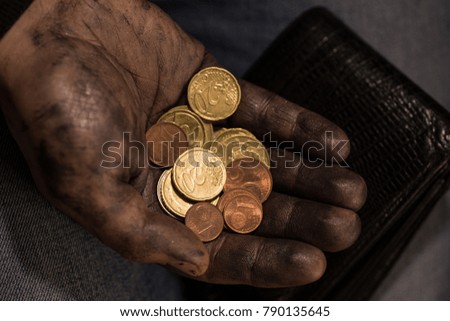 Dirty working palm with coins, a purse with coins