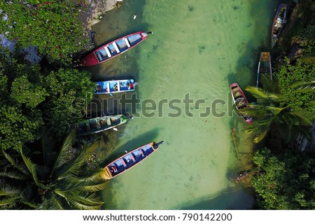 Aerial shot of White River, Ochios Rios, Jamaica with 4 colorful fishing boat moored in a small fishing settlement. Fishes are visible through the clear waters.