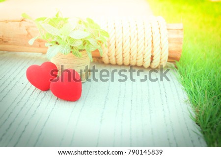Two red hearts and a small tree placed on a green grass.