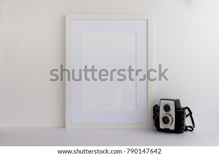 A4 A3 A5 white wooden picture frame with white blank space for your quote, logo or work or for overlay standing next to vintage camera. Blank space for bloggers, marketers or website designers.