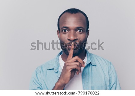 Just don't speak! Close up portrait of handsome cheerful mysterious silent man making hush gesture, isolated on gray background
