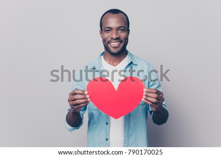 Be my girlfriend! I love you! Portrait of tender gentle romantic sweet lovely open-hearted african man showing big red heart in hands isolated on gray background