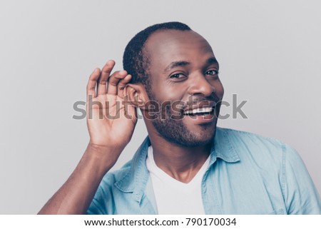 Close up portrait of curious interested delightful funny amazed cheerful surprised african man holding hand near ear and trying to hear the information isolated on gray background Royalty-Free Stock Photo #790170034